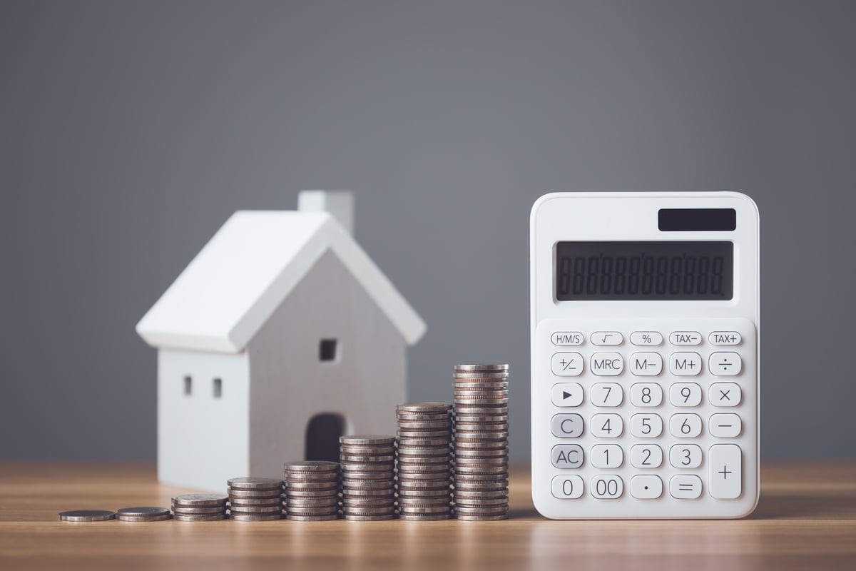 A house and calculator with a stack of coins