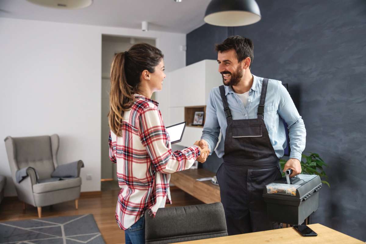 Repairman shaking hands with a woman in a home, property management companies in Indianapolis concept