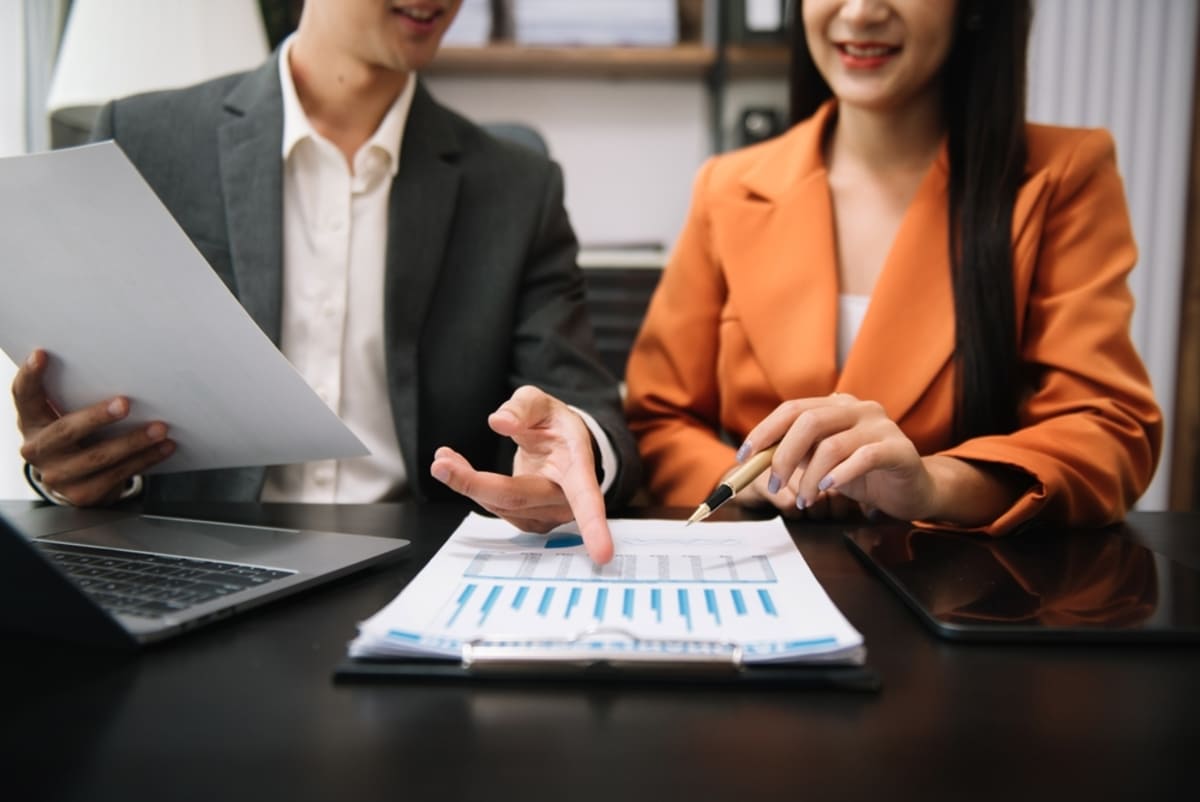 Two people looking at a paper with charts and data on it, property management rental analysis concept